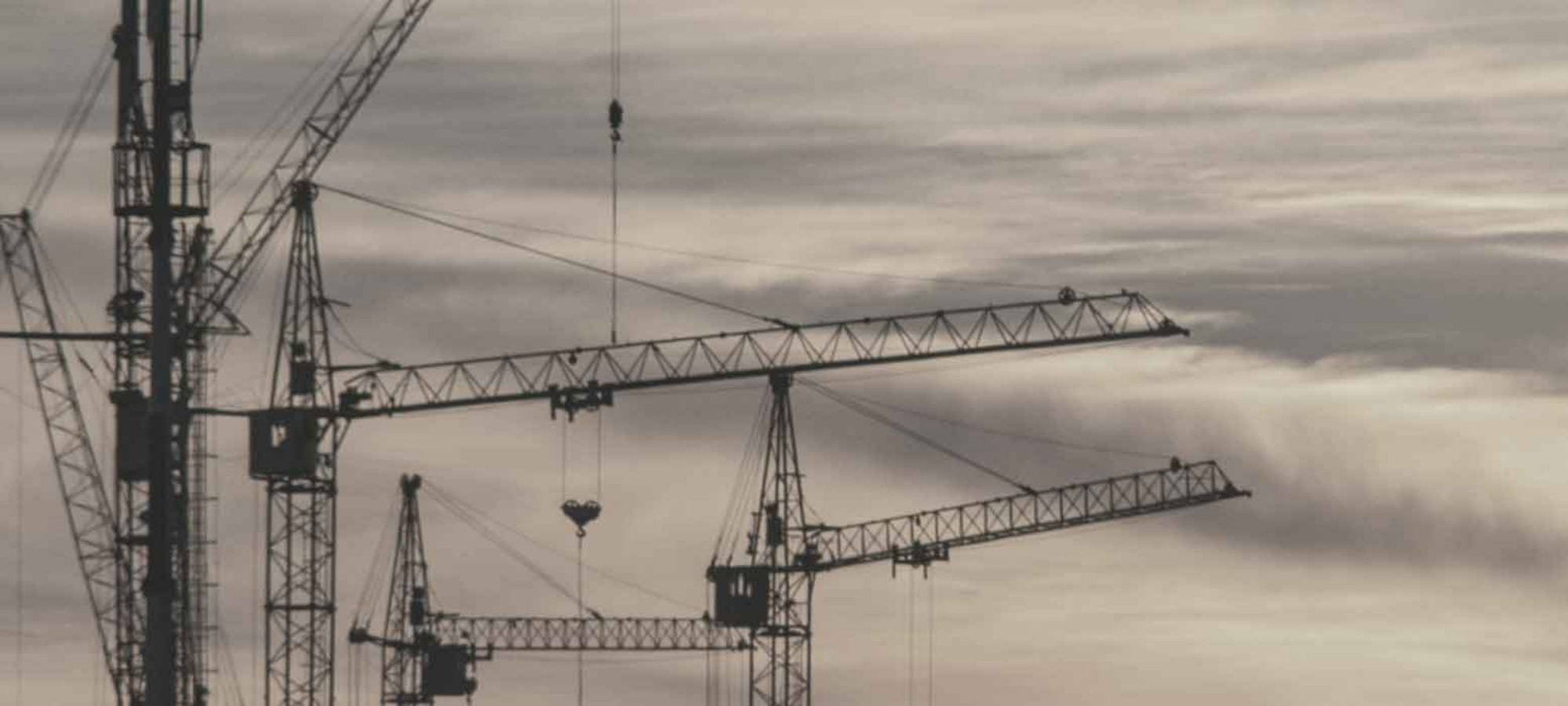 greyscale image of cranes against sky